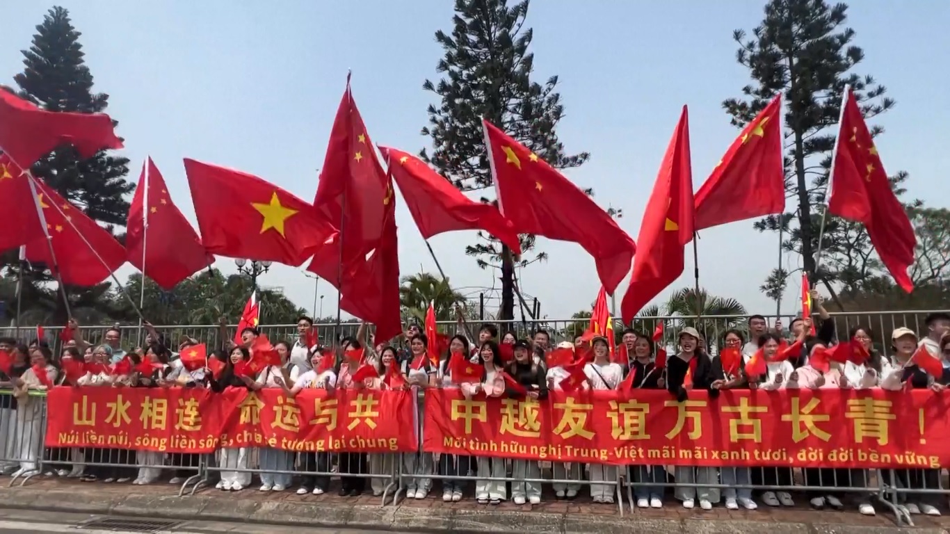 Sambil melambaikan bendera nasional Tiongkok dan Vietnam serta membawa spanduk selamat datang yang besar