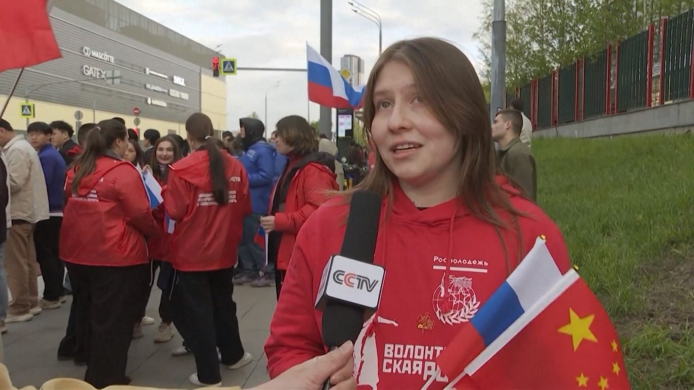 Kerumunan orang yang menyambut terlihat melambaikan bendera nasional Tiongkok dan Rusia untuk menyambut Presiden Tiongkok saat iring-iringan mobilnya lewat